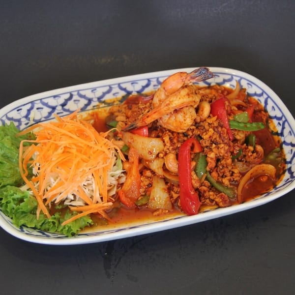 Spicy Thai dish with ground meat, shrimp, cashews, bell peppers, and shredded carrots on a patterned plate.