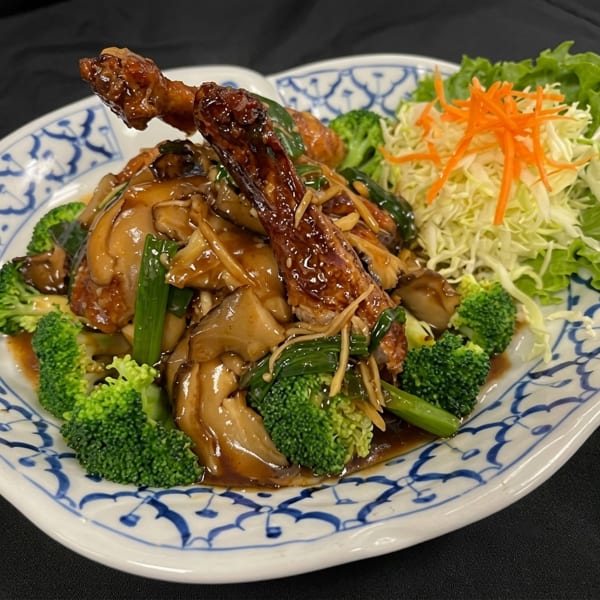 Crispy duck with mushrooms, broccoli, and green onions in a rich brown sauce, served with shredded cabbage.